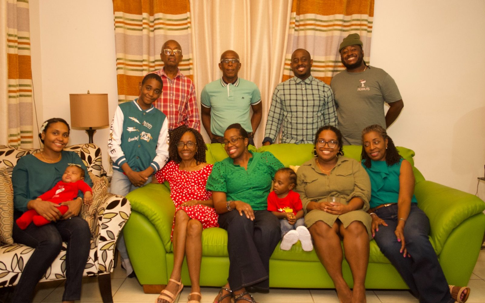 Dr. Keri with her family in Trinidad, four generations on and around a green sofa.